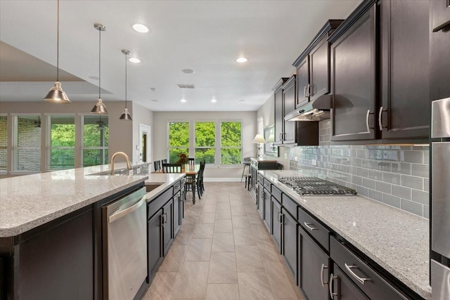 6514 Eagle Rock Dr, Frisco, TX 75036 - kitchen featuring under cabinet range hood, stainless steel appliances, backsplash, a sink, and a kitchen island with sink