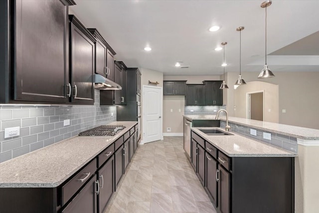 6514 Eagle Rock Dr, Frisco, TX 75036 - kitchen featuring stainless steel gas stovetop, an island with sink, under cabinet range hood, a sink, and decorative backsplash