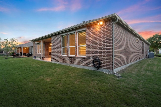 6514 Eagle Rock Dr, Frisco, TX 75036 - property exterior at dusk featuring brick siding, a yard, cooling unit, and a patio