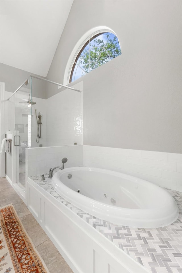 full bath featuring a ceiling fan, vaulted ceiling, a tub with jets, and a stall shower