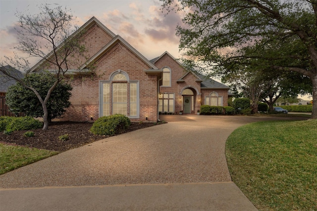 french country home with brick siding and driveway