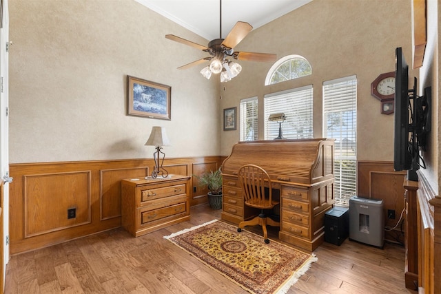 office area featuring a ceiling fan, a wainscoted wall, light wood-style floors, and ornamental molding