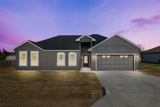 view of front of house featuring concrete driveway, a front lawn, roof with shingles, and a garage