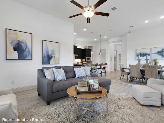 living area featuring light wood-type flooring, a ceiling fan, visible vents, and recessed lighting