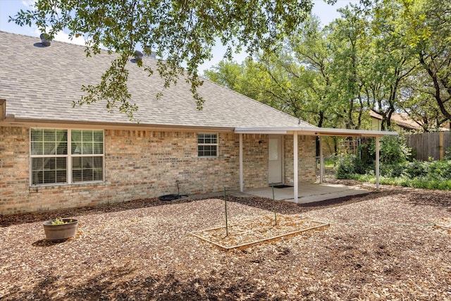 back of property with brick siding, fence, a patio area, and a shingled roof