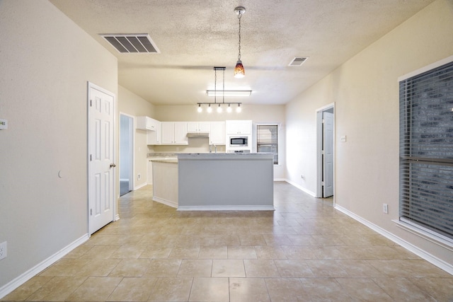 803 Sterling Ct, Allen, TX 75002 - kitchen featuring stainless steel microwave, a textured ceiling, white cabinetry, decorative light fixtures, and light tile patterned flooring