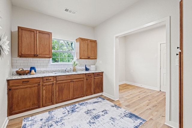 1031 W Chestnut St, Denison, TX 75020 - kitchen with a sink, backsplash, light wood-style floors, and brown cabinets