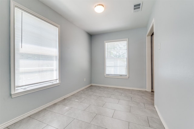 unfurnished room featuring baseboards, visible vents, and light tile patterned floors
