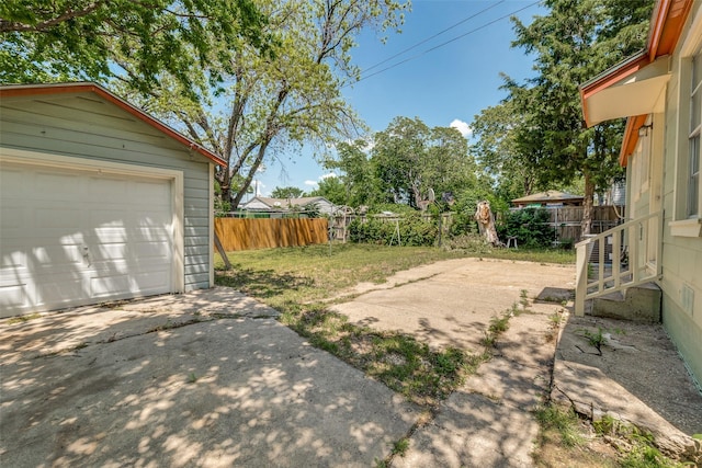 view of yard with fence, an outbuilding, and concrete driveway