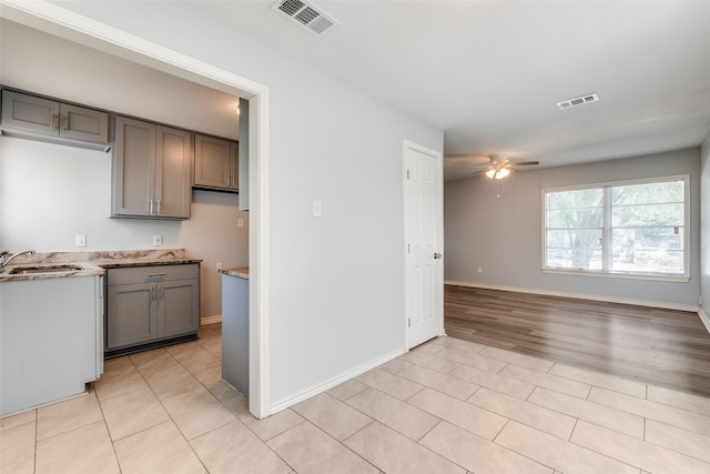 kitchen with ceiling fan, gray cabinetry, a sink, and visible vents