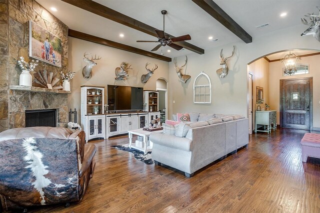 living area featuring beamed ceiling, a ceiling fan, visible vents, and arched walkways
