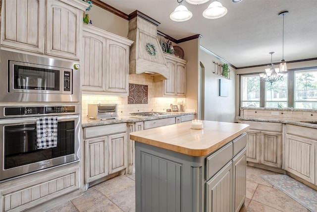 kitchen featuring backsplash, appliances with stainless steel finishes, crown molding, and a kitchen island