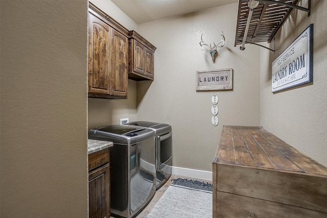laundry room featuring washing machine and clothes dryer, cabinet space, a textured wall, and baseboards