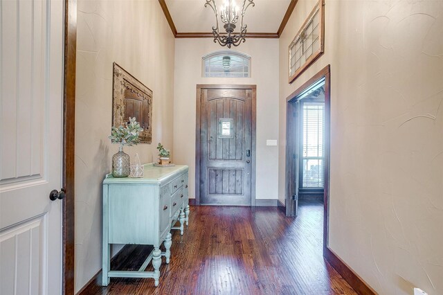 foyer with dark wood finished floors, ornamental molding, baseboards, and a notable chandelier