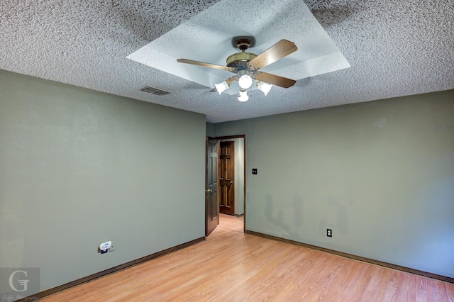 unfurnished room with a ceiling fan, a textured ceiling, light wood finished floors, baseboards, and visible vents