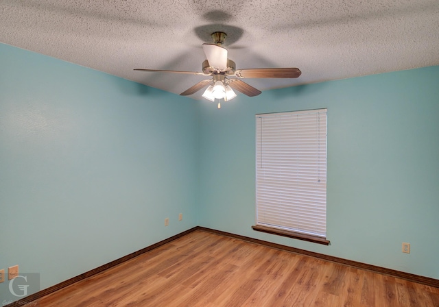 spare room featuring wood finished floors, a textured ceiling, baseboards, and ceiling fan