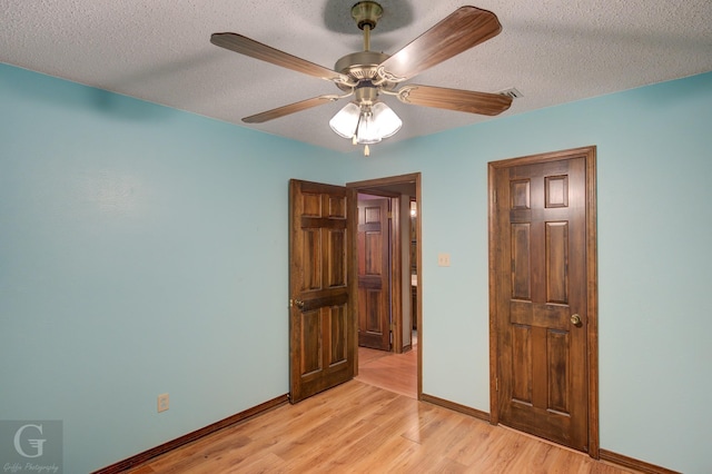 bedroom featuring light wood-type flooring, a ceiling fan, baseboards, and a textured ceiling