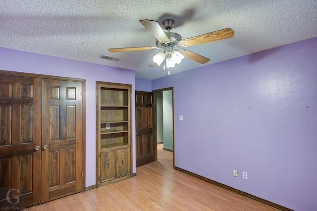 unfurnished bedroom with visible vents, light wood-type flooring, baseboards, a textured ceiling, and ceiling fan
