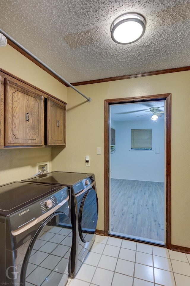 washroom with light tile patterned floors, washer and dryer, cabinet space, baseboards, and ornamental molding