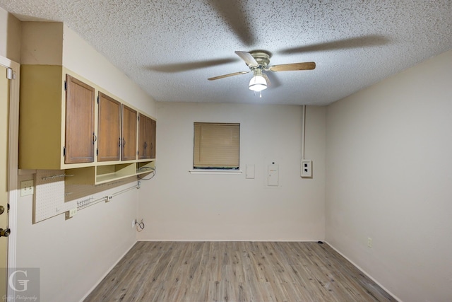 clothes washing area featuring a textured ceiling, light wood-style floors, and ceiling fan