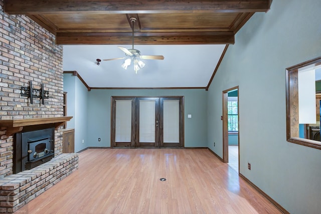 unfurnished living room with a ceiling fan, lofted ceiling with beams, light wood-type flooring, a fireplace, and baseboards