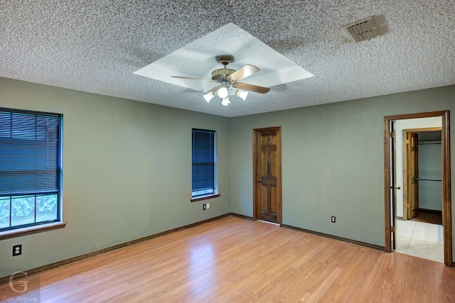 unfurnished bedroom featuring a textured ceiling, visible vents, light wood finished floors, and baseboards