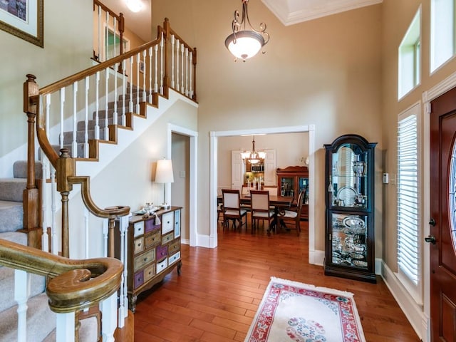 entryway with wood-type flooring, a high ceiling, a healthy amount of sunlight, and stairway