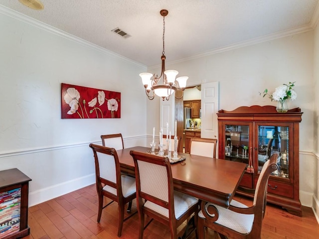 dining area featuring visible vents, crown molding, baseboards, a chandelier, and light wood-style floors