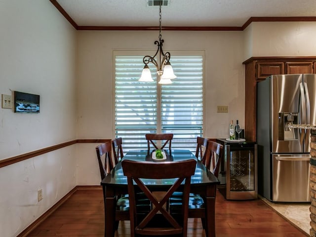 dining area featuring wine cooler, ornamental molding, hardwood / wood-style floors, and a notable chandelier