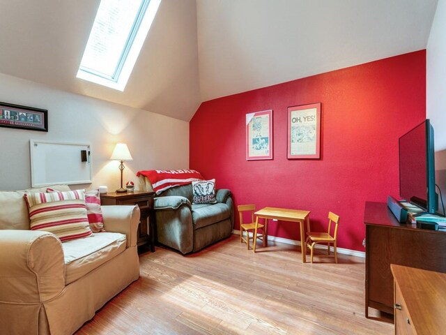 bedroom with light wood-style floors and lofted ceiling with skylight