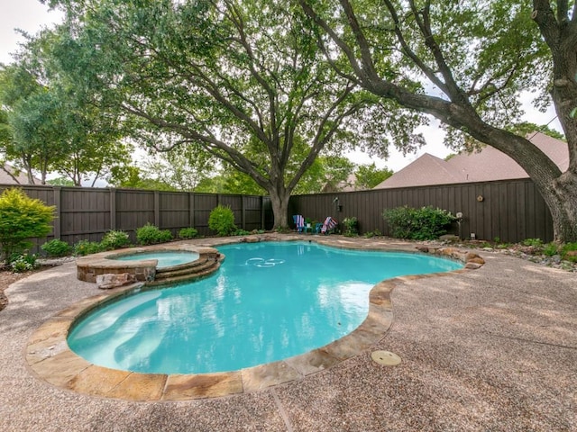 view of swimming pool featuring a fenced backyard and a pool with connected hot tub