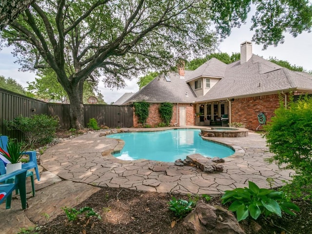 view of pool featuring a fenced backyard, a pool with connected hot tub, and a patio area