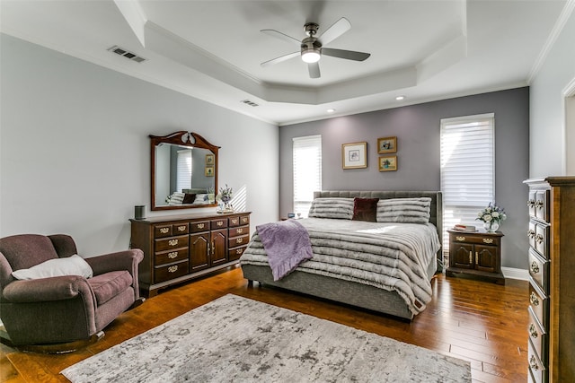 bedroom with visible vents, ornamental molding, dark wood-type flooring, and a tray ceiling