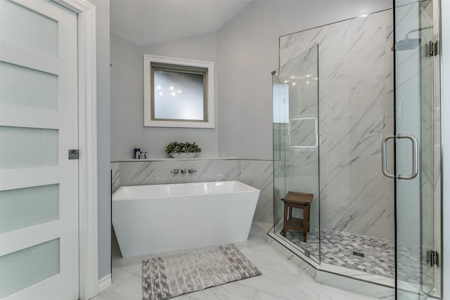 full bath featuring a marble finish shower, marble finish floor, a freestanding tub, tile walls, and vaulted ceiling