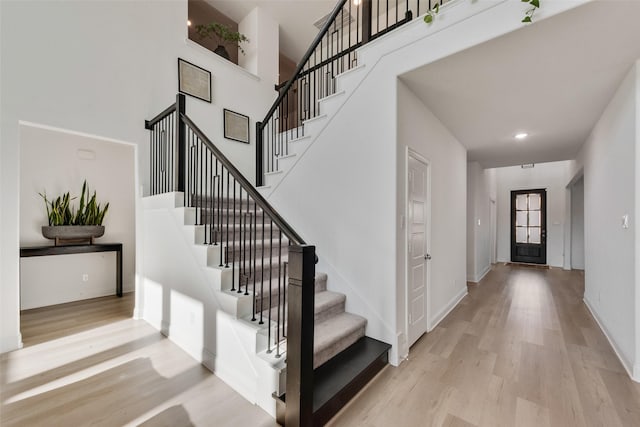 entryway with stairway, a high ceiling, wood finished floors, and baseboards