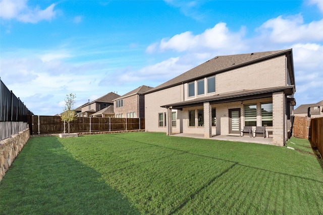 back of house with a patio area, a fenced backyard, brick siding, and a yard