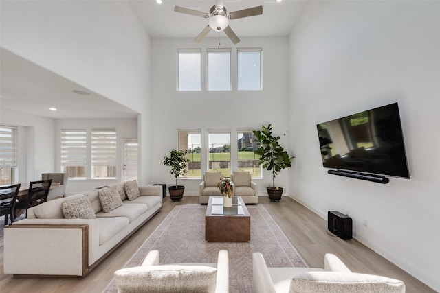living area with light wood-style flooring, a wealth of natural light, and a ceiling fan