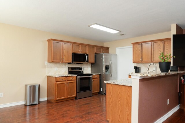 kitchen featuring decorative backsplash, a peninsula, baseboards, dark wood finished floors, and appliances with stainless steel finishes