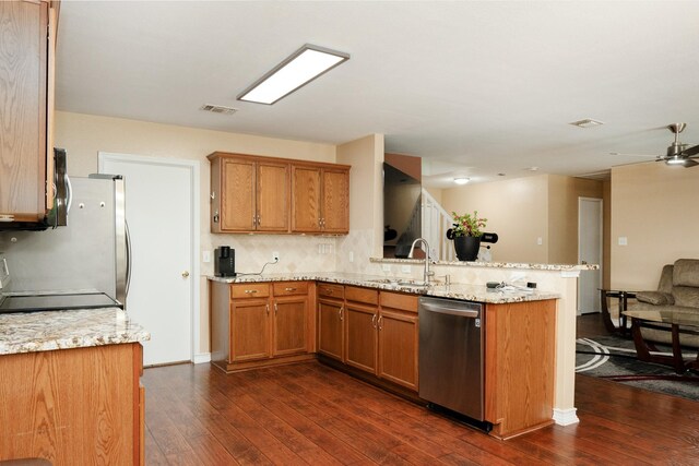 kitchen featuring appliances with stainless steel finishes, brown cabinets, dark wood-style flooring, and a peninsula