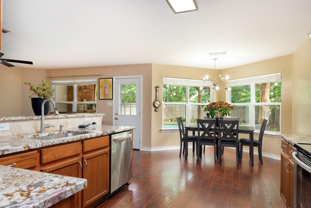 kitchen with brown cabinets, baseboards, appliances with stainless steel finishes, and a sink