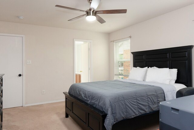 bedroom with a ceiling fan, baseboards, light colored carpet, and ensuite bath