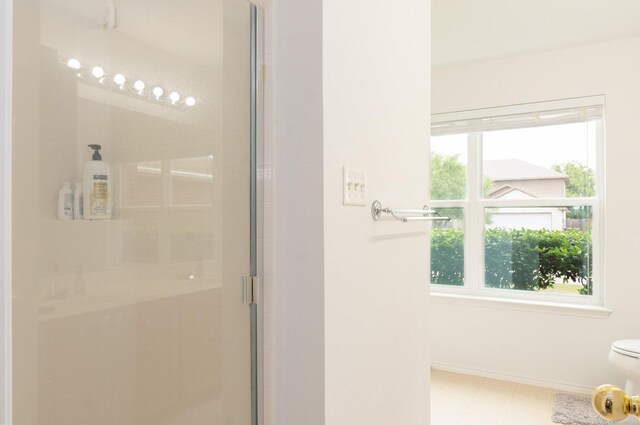 bathroom featuring toilet, baseboards, and a stall shower