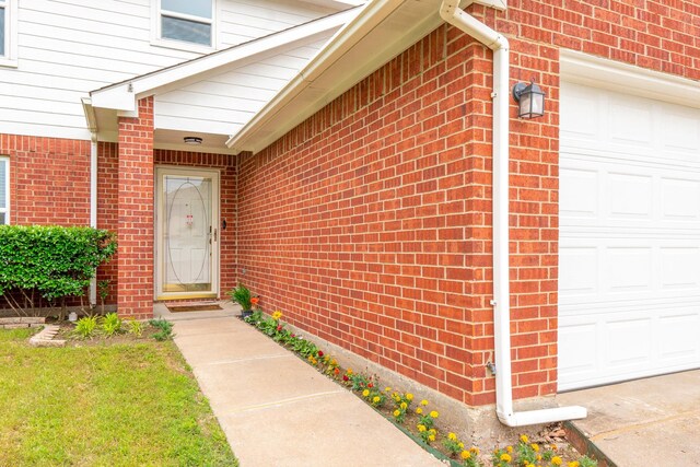 entrance to property with brick siding and a garage
