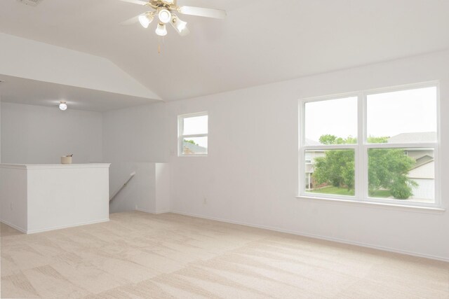 unfurnished room featuring ceiling fan, vaulted ceiling, light carpet, and baseboards