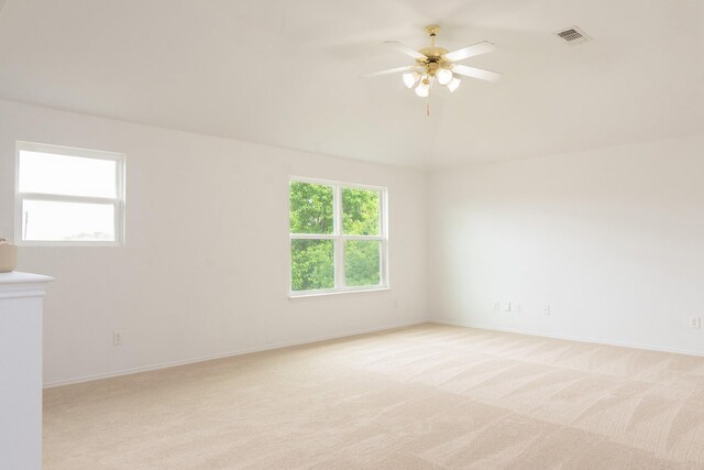empty room featuring light colored carpet, a ceiling fan, baseboards, and visible vents
