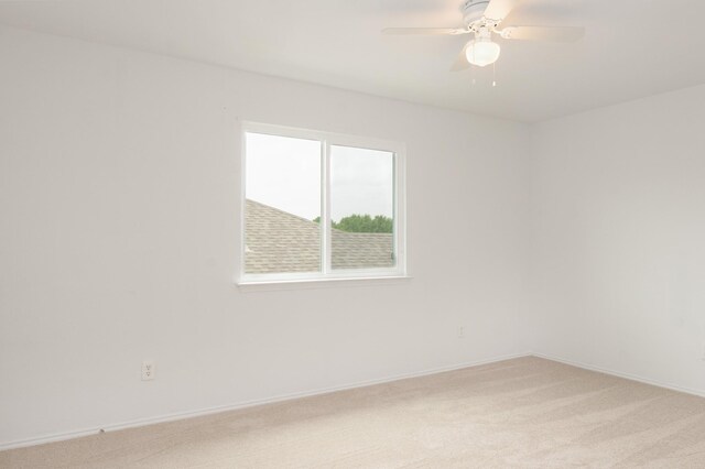 spare room with light colored carpet, baseboards, and ceiling fan