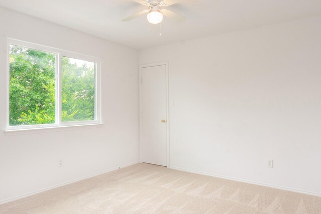 empty room with a ceiling fan, baseboards, light carpet, and a healthy amount of sunlight