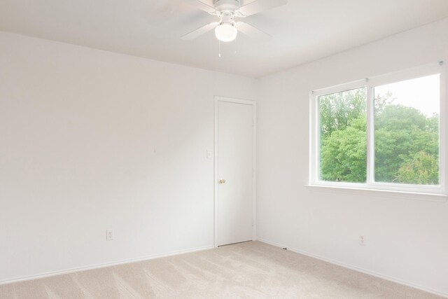 unfurnished room with baseboards, light carpet, and a ceiling fan