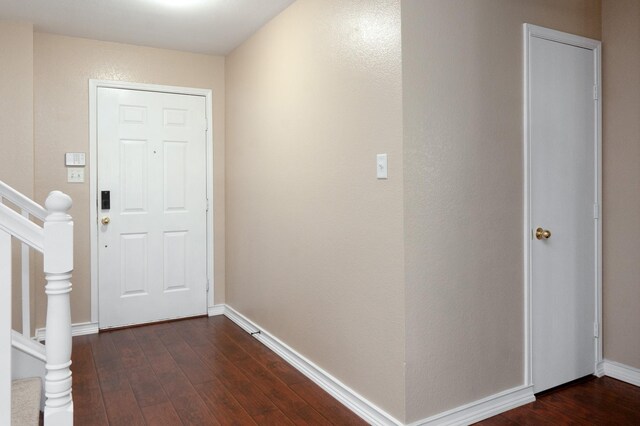 foyer featuring baseboards, dark wood finished floors, and stairway
