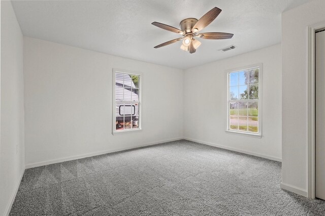carpeted spare room featuring baseboards, a ceiling fan, and visible vents